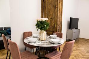 een eettafel met stoelen en een vaas met bloemen bij CracWoW K8 No.10 Apartment in Krakau