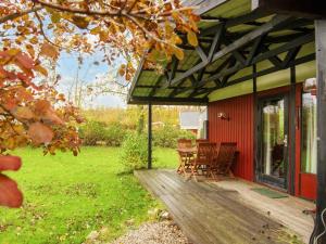 eine Veranda eines roten Hauses mit einem Tisch und Stühlen in der Unterkunft Holiday home Sydals XXXI in Neder Lysabild