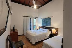 a bedroom with two beds and a table and a chair at Pousada Coqueiro Verde in Itacaré