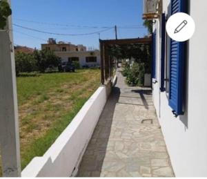 a sidewalk next to a building with a blue shutter at A CASA D'IRENE in Votsalákia +7 photos