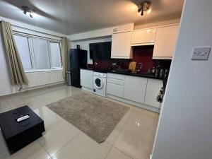 a kitchen with white cabinets and a washer and dryer at Lovely 1 bedroom flat in Chigwell