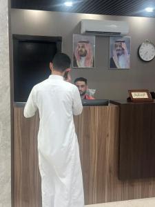 a man standing at a counter talking on a wii controller at كازا رست للوحدات السكنية in Ḩayy aş Şāliḩīyah