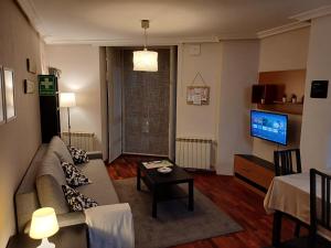ein Wohnzimmer mit einem Sofa und einem TV in der Unterkunft Apartamento Galería Gijón in Gijón