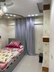 1 dormitorio con 1 cama con cortina púrpura en Mini VELLA ALJWHARA en Al Ḩammām