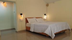 a bedroom with a bed with white sheets and pillows at Jardim De Sanfrancisco in Agonda