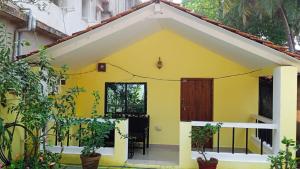 a yellow house with a door and plants at Jardim De Sanfrancisco in Agonda