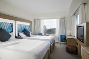 a hotel room with two beds and a television at Novotel Tainui Hamilton in Hamilton