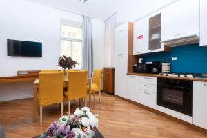 布拉格的住宿－Moonlight Apartments Old Town，厨房配有白色橱柜和一张带黄色椅子的桌子