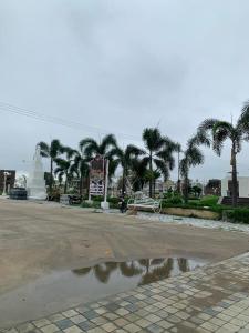 a parking lot with palm trees and a puddle of water at Away From Home, Furnished Apartment in Bhopal