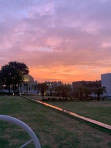 a park at sunset with a building in the background at Away From Home, Furnished Apartment in Bhopal
