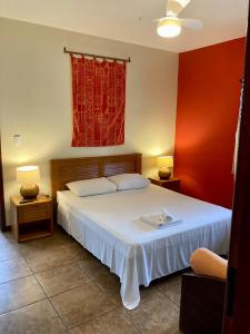 a bedroom with a white bed and red walls at Pousada Coqueiro Verde in Itacaré