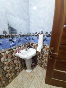 a bathroom with a sink and a rock wall at Erki Guest House in Abu Simbel