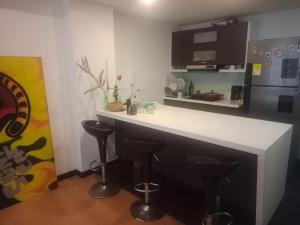 une cuisine avec un comptoir blanc et des tabourets dans l'établissement Habitaciones Centro Histórico, ed, continental, à Bogotá