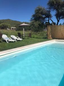 una piscina con 2 sillas y una sombrilla en Cabaña Privada en Comuna San Roque en Bialet Massé