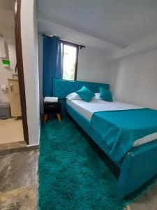 una camera con un letto blu e un tappeto verde di Apartamentos Quimbaya a Quimbaya