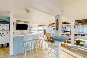 a kitchen with a bar with stools and a tv at The Swordfish Sanctuary in Galveston
