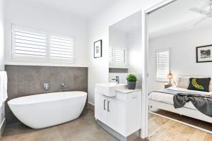 a white bathroom with a tub and a bed at Flagship Villa in Trinity Beach