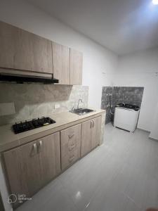 una cocina con armarios de madera, fregadero y electrodomésticos en EDIFICIO BUENOS AIRES 1 Habitación en Sincelejo