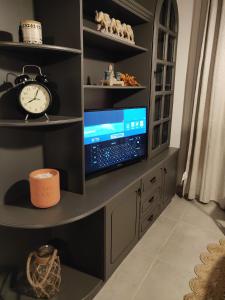 a room with a desk with a tv and a clock at Central Malta Apartment in Birkirkara