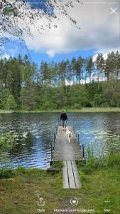 a person walking a dog on a wooden bridge over a lake at Independent apartment in Borås in Borås