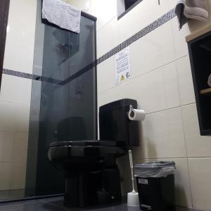 a bathroom with a toilet and a glass wall at Hospedagem Costa BNU - PLUS in Blumenau