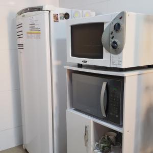 un horno microondas sobre una nevera en Hospedagem Costa BNU - PLUS en Blumenau