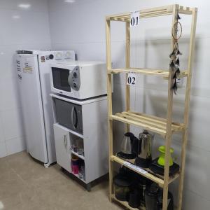 a shelf in a kitchen with a microwave and a refrigerator at Hospedagem Costa BNU - PLUS in Blumenau
