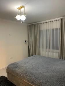 a bedroom with a bed and a lamp and a window at Scandinavia Mountain View Apartment in Piatra Neamţ