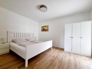 a white bedroom with a bed and a white cabinet at Haus No. 48 in Friesenheim