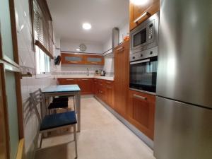 a kitchen with wooden cabinets and a stainless steel refrigerator at EL RINCÓN DEL GUADALQUIVIR in La Rinconada