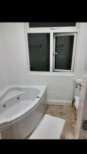 eine weiße Badewanne im Bad mit Fenster in der Unterkunft Mirandas Place in Gillingham