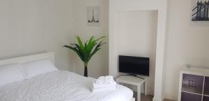 Schlafzimmer mit einem weißen Bett und einem TV in der Unterkunft Mirandas Place in Gillingham