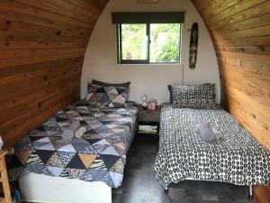two beds in a small room with a window at The Dome Waikino in Waikino