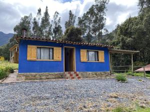 a blue house on a gravel driveway at La Roca Glamping in Arcabuco