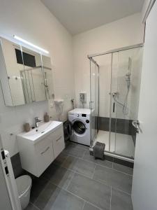 een badkamer met een douche, een wastafel en een wasmachine bij Cozy Homes Vienna in Wenen