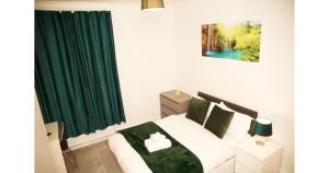a bedroom with a bed with a green curtain at Cricklewood Deluxe Ensuite Room in London