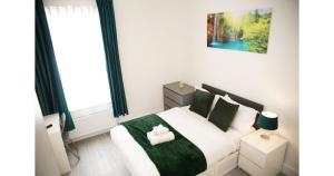 a bedroom with a white bed with a green blanket at Cricklewood Deluxe Ensuite Room in London