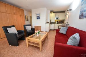 Sala de estar con 2 sofás rojos y mesa de centro en Haus "Atlantic" Appartement ATL303, en Cuxhaven