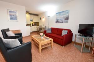 sala de estar con 2 sillas y sofá rojo en Haus "Atlantic" Appartement ATL303, en Cuxhaven