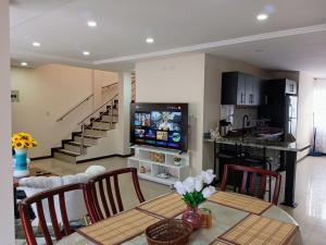 a kitchen and dining room with a table and a television at Departamento Grande con Jacuzzi in Cuenca