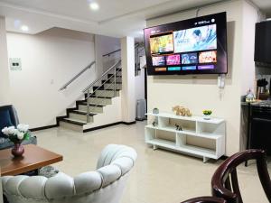 uma sala de estar com um sofá e uma televisão na parede em Departamento Grande con Jacuzzi em Cuenca