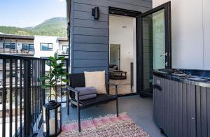 a small house with a chair on a balcony at The Stoke Stopover - Revelstoke Condo with Hot Tub in Revelstoke