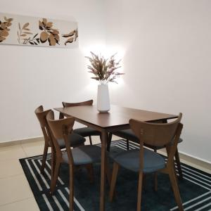 a dining room table with chairs and a vase with a plant at ART CASIA HOMESTAY BERTAM in Kepala Batas