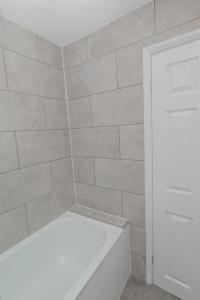 a bathroom with a white tub and a tile wall at The house in Barking