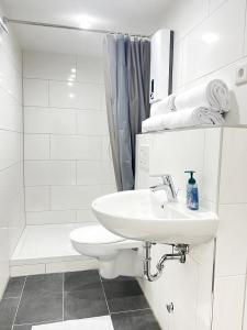 y baño blanco con lavabo y ducha. en Wohnung alleinige Nutzung 30qm 4 Schlafplätze Wiesbaden, en Walluf