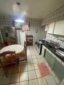 a small kitchen with a table and a refrigerator at Casa Gaúcho in Morro de São Paulo
