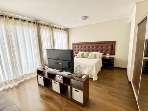 a bedroom with a bed and a tv on a table at Departamento Elegante y Relax by Torre Vento in Santa Cruz de la Sierra