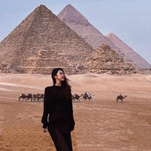 Una donna è in piedi davanti alle piramidi di Discover pyramids inn a Il Cairo
