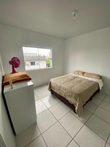 a white bedroom with a bed and a window at Apartamento no centro com suíte in Ametista do Sul