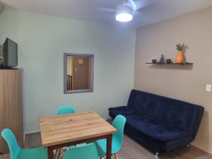 ein Wohnzimmer mit einem blauen Sofa und einem Tisch in der Unterkunft Apartamento 50 metros do Mar da Brava Floripa in Florianópolis